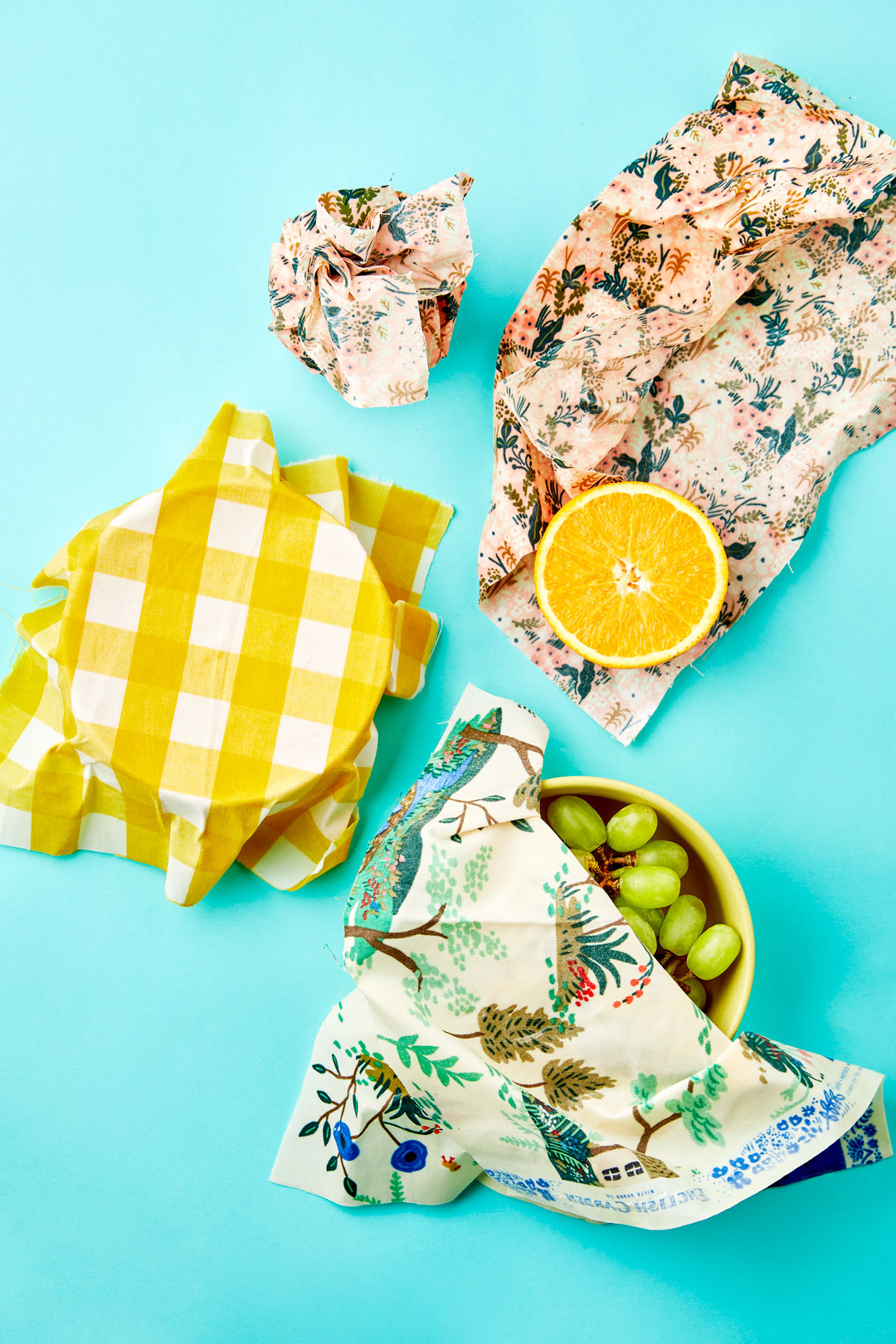 How to make your own beeswax wraps: bowl, grapes, and an orange wrapped in DIY beeswax wraps
